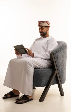 رجل عُماني بالزي التقليدي يستخدم جهازاً لوحياً في الاستوديو