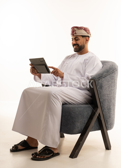 رجل عماني بالزي التقليدي يستخدم جهاز لوحي