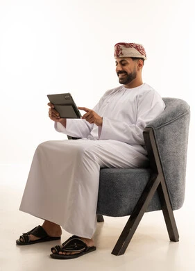 رجل عماني بالزي التقليدي يستخدم جهاز لوحي