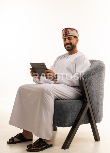 Omani Man with Tablet in Traditional White Dishdasha