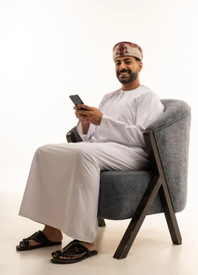 رجل عماني بالزي التقليدي يستخدم الهاتف الذكي