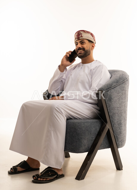 رجل عماني باللباس التقليدي يتحدث عبر الهاتف الذكي