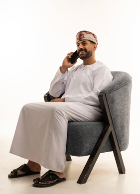 رجل عماني باللباس التقليدي يتحدث عبر الهاتف الذكي