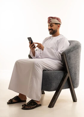 رجل عماني باللباس التقليدي يستخدم الهاتف الذكي