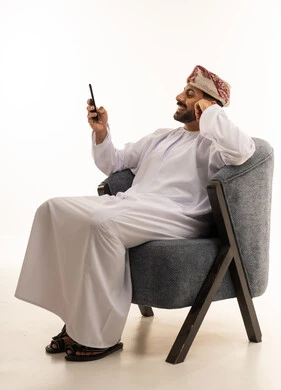 رجل عماني بالزي التقليدي يستخدم الهاتف الذكي