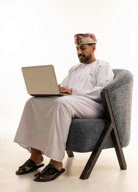 رجل عماني يستخدم الحاسوب المحمول بالزي التقليدي