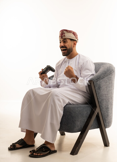 رجل عماني بالزي التقليدي يلعب ألعاب الفيديو