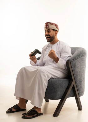 رجل عماني بالزي التقليدي يلعب ألعاب الفيديو