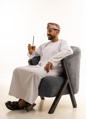 Omani Man in Traditional Dress Sitting with Juice