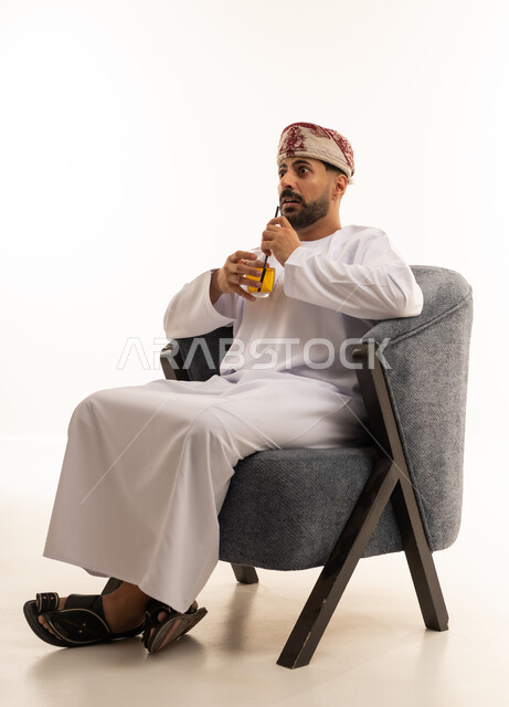 Omani Man in Traditional Dress Sitting with Juice