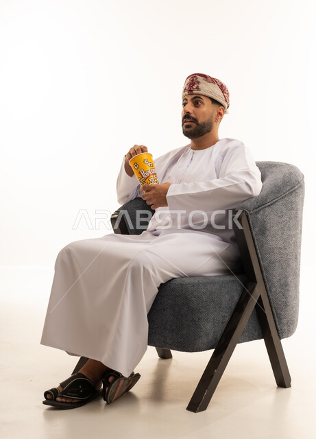 Omani Man in Traditional Dress Eating Popcorn