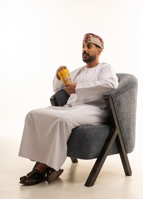 رجل عماني بالزي التقليدي يأكل الفشار