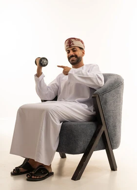 رجل عُماني يحمل ثقل حديدي جالس في استوديو