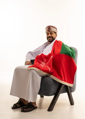 رجل عماني باللباس التقليدي والعلم الوطني