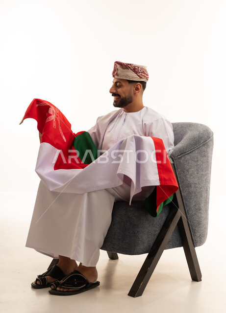 رجل عماني بالزي التقليدي يمسك علم سلطنة عمان