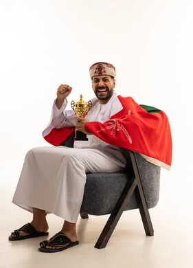 رجل عماني يحمل كأس ذهبي وعلم عمان