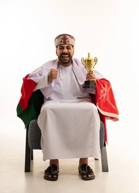 رجل عماني يحمل كأساً ذهبية مع العلم الوطني