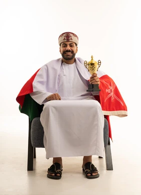 رجل عماني يحمل كأساً ذهبياً مع العلم الوطني