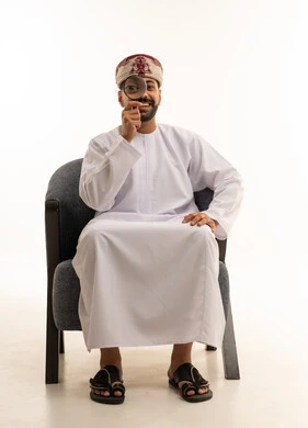 رجل عُماني يحمل عدسة مكبرة في الاستوديو