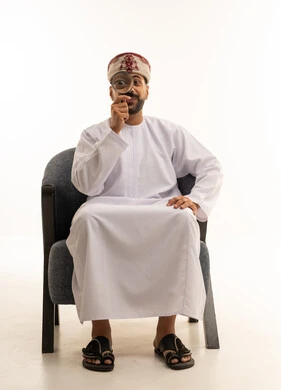 رجل عماني بالزي التقليدي مع عدسة مكبرة