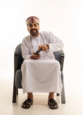 شاب عُماني بالزي التقليدي يمسك بجهاز تحكم ألعاب الفيديو