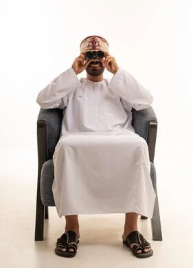 رجل عماني بالزي التقليدي يستخدم المنظار