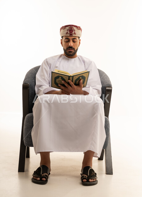 رجل عماني بالزي التقليدي يقرأ القرآن الكريم