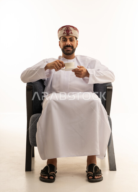 رجل عماني بالزي التقليدي يشرب القهوة في الاستوديو