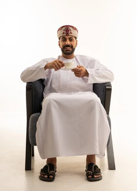 رجل عماني بالزي التقليدي يشرب القهوة في الاستوديو