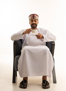 رجل عماني بالزي التقليدي يشرب القهوة