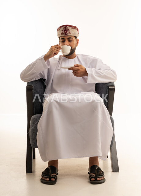 Omani Man in Traditional Dishdasha Drinking Coffee