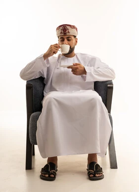 رجل عماني بالزي التقليدي يشرب القهوة