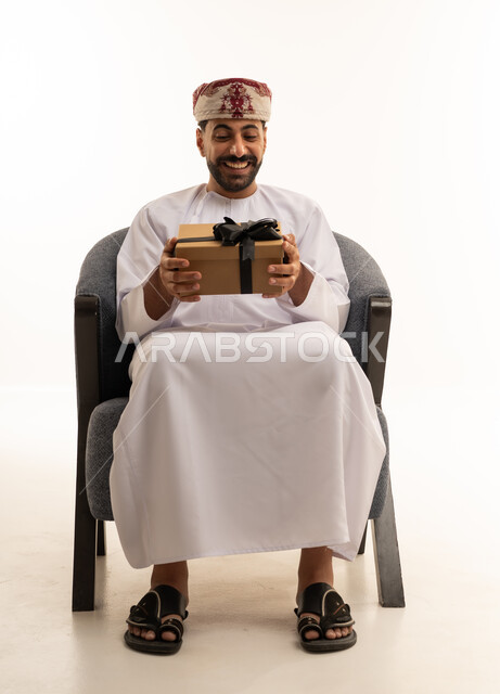 Omani Man in Traditional Dress Holding Gift Box