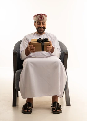 رجل عماني بالزي التقليدي يحمل هدية