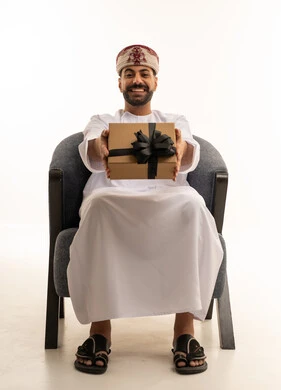 Omani Man in Traditional Dress Holding Gift Box