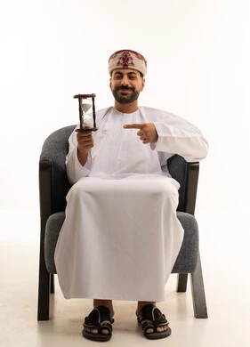 رجل عماني بالزي التقليدي يمسك ساعة رملية