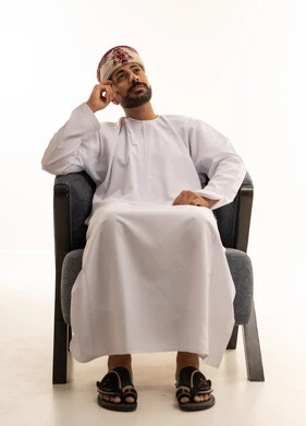 رجل عماني بالزي التقليدي والدشداشة يفكر في استوديو