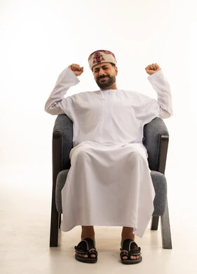 Omani Man in Traditional Dishdasha Sitting on Armchair