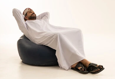 رجل عماني يسترخي على كرسي بين باج خلفية بيضاء