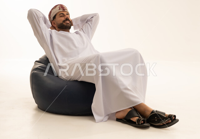 Omani Man in Traditional Dress Relaxing on Bean Bag