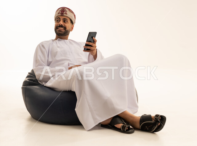رجل عُماني مع هاتف ذكي على مقعد محشو