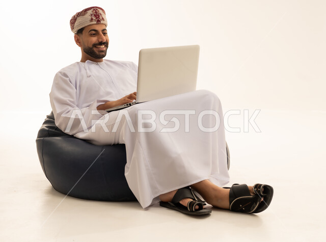 Omani Man Using Laptop on Bean Bag