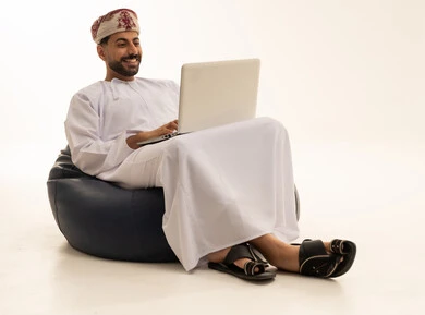 رجل عماني يستخدم الحاسوب المحمول على خلفية بيضاء