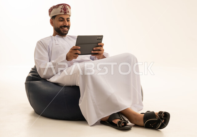 رجل عُماني يستخدم جهازاً لوحياً في الاستوديو