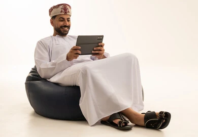 رجل عُماني يستخدم جهازاً لوحياً في الاستوديو