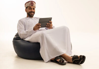 رجل عماني بجهاز لوحي على مقعد مريح