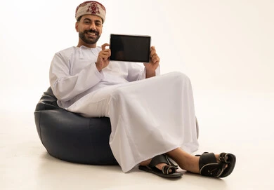 رجل عماني يمسك جهاز لوحي على خلفية بيضاء