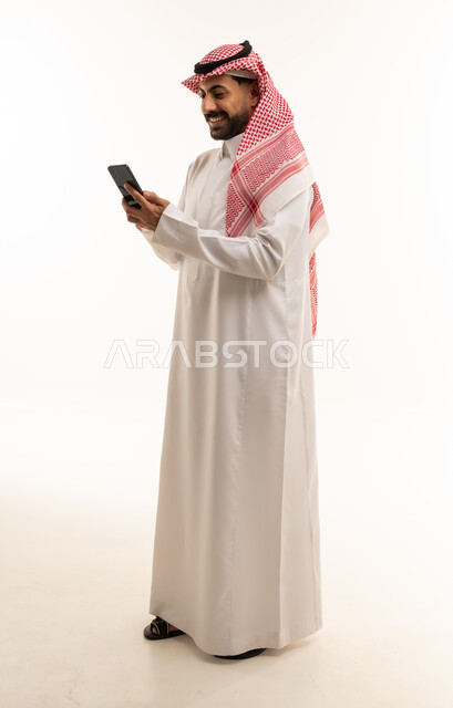 رجل سعودي بالثوب يستخدم الهاتف الذكي خلفية بيضاء