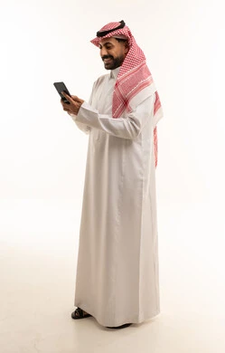 رجل سعودي بالثوب يستخدم الهاتف الذكي خلفية بيضاء