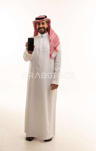 رجل سعودي بالثوب التقليدي يمسك هاتف جوال